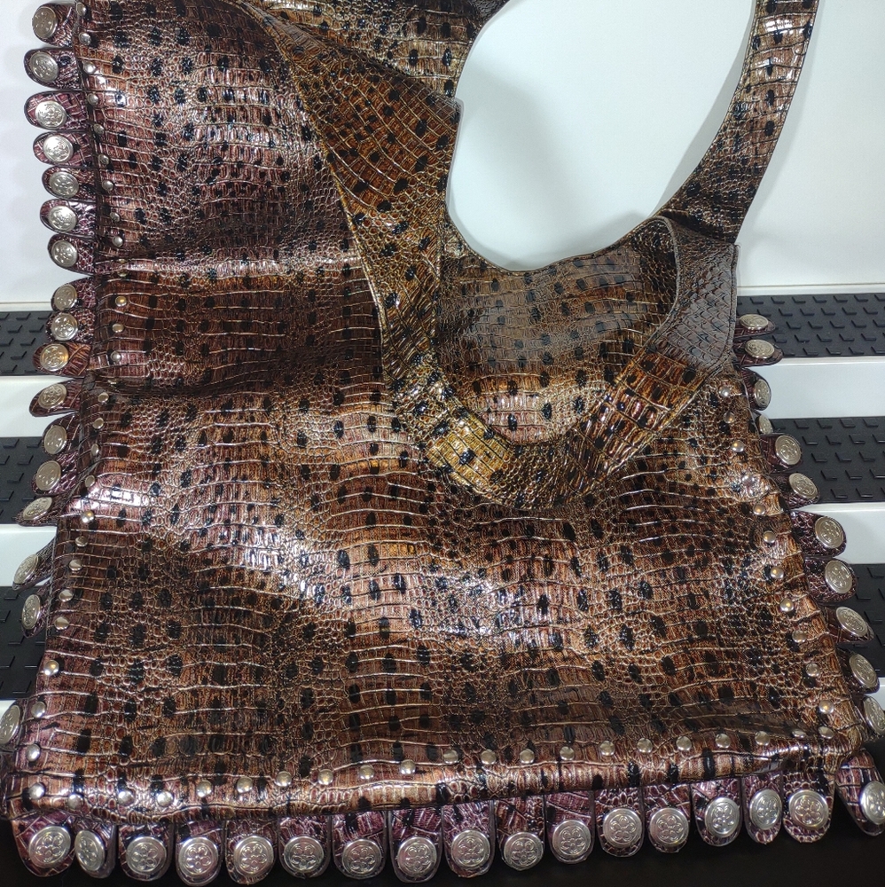 Reptile like bag , surrounded by decorative snaps, and studs.